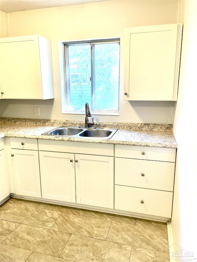 kitchen with light countertops, a sink, and white cabinetry