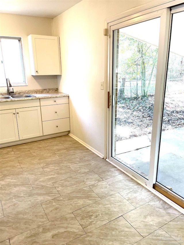 kitchen featuring light countertops, a sink, white cabinets, and a healthy amount of sunlight