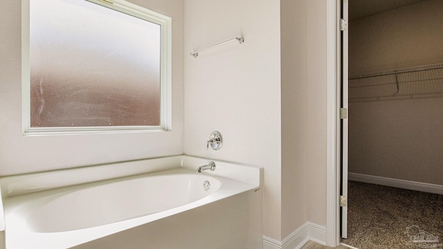 8616 Bluebell St, Milton, FL 32583 - bathroom featuring a garden tub, a walk in closet, and baseboards