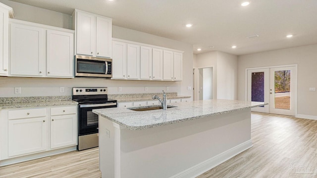 8616 Bluebell St, Milton, FL 32583 - kitchen featuring appliances with stainless steel finishes, a sink, light wood finished floors, a center island with sink, and recessed lighting