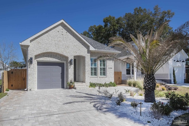 view of front of property with a garage, decorative driveway, a shingled roof, and a gate