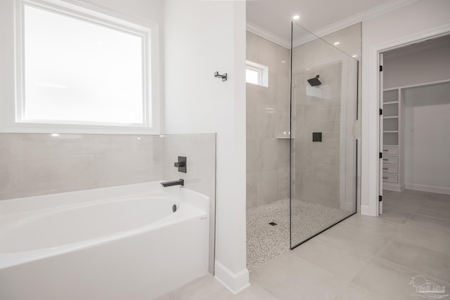 bathroom featuring a walk in shower, a walk in closet, crown molding, baseboards, and a bath