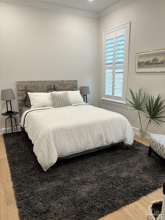 bedroom featuring ornamental molding, baseboards, and wood finished floors