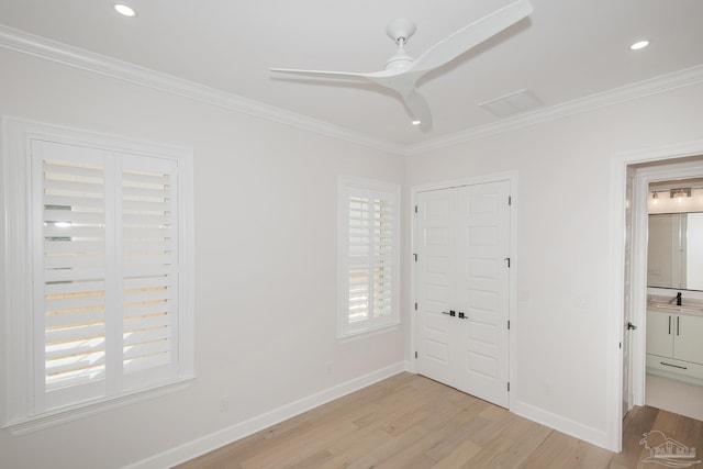 unfurnished bedroom featuring a sink, baseboards, light wood-style flooring, and crown molding