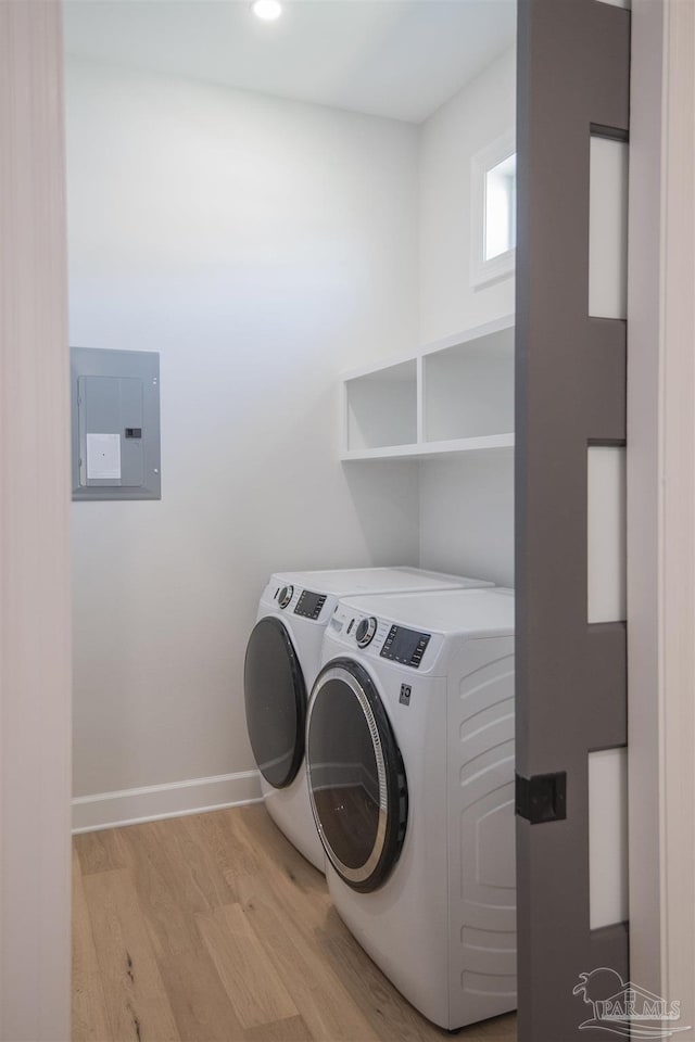 washroom featuring electric panel, light wood-style floors, separate washer and dryer, baseboards, and laundry area