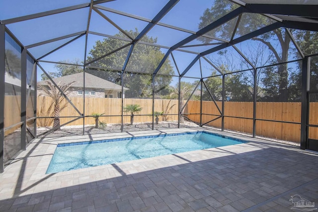 view of swimming pool with glass enclosure, a patio, a fenced backyard, and a fenced in pool