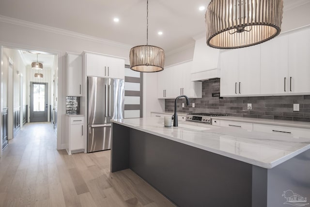 kitchen with crown molding, premium range hood, light wood-type flooring, stainless steel appliances, and a sink