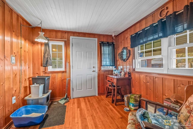 interior space with crown molding, light hardwood / wood-style flooring, wooden ceiling, and wooden walls