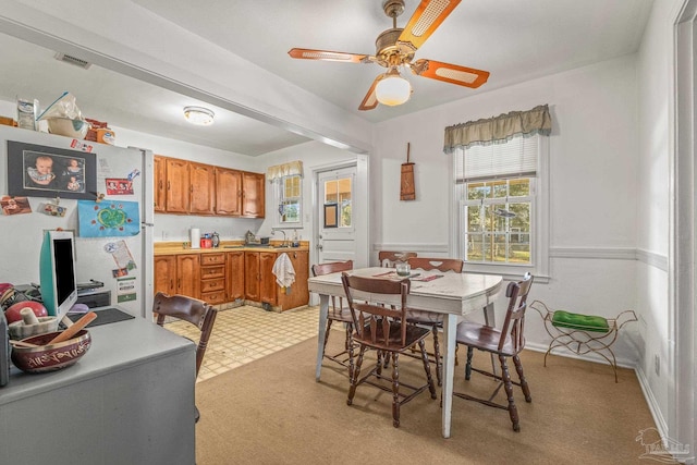 dining area featuring ceiling fan and light colored carpet