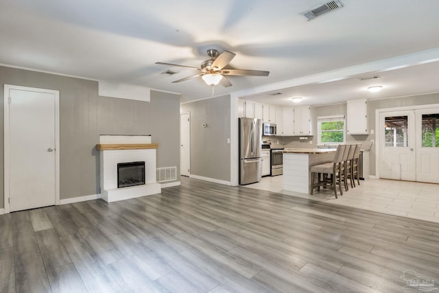 6845 Trail Ride S, Milton, FL 32570 - living area with ceiling fan, light wood-style flooring, a brick fireplace, baseboards, and crown molding