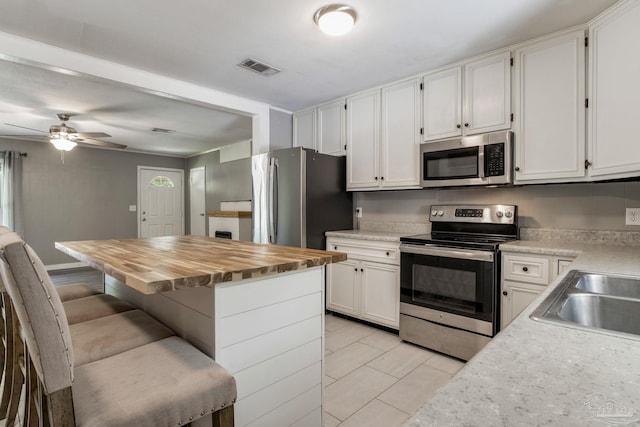 6845 Trail Ride S, Milton, FL 32570 - kitchen with stainless steel appliances, white cabinetry, wood counters, a breakfast bar, and ceiling fan