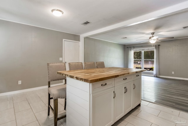 6845 Trail Ride S, Milton, FL 32570 - kitchen featuring butcher block counters, a kitchen breakfast bar, a ceiling fan, white cabinetry, and a kitchen island