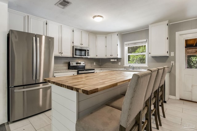 6845 Trail Ride S, Milton, FL 32570 - kitchen with stainless steel appliances, a sink, butcher block countertops, and white cabinetry