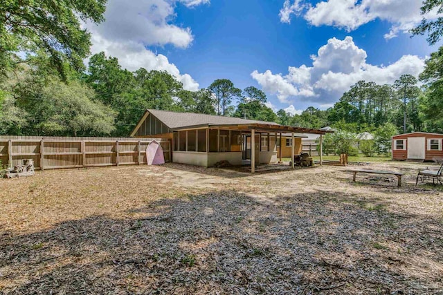 6845 Trail Ride S, Milton, FL 32570 - rear view of property featuring a sunroom, fence, an outbuilding, a storage shed, and view of scattered trees
