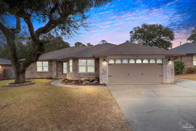 ranch-style house featuring roof with shingles, an attached garage, concrete driveway, a front lawn, and brick siding