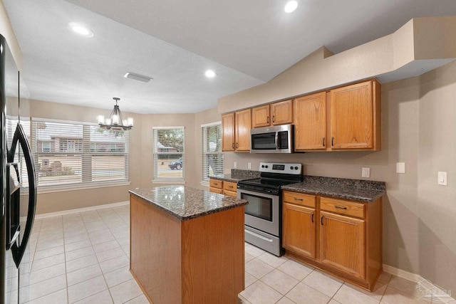 kitchen with visible vents, a kitchen island, appliances with stainless steel finishes, an inviting chandelier, and brown cabinetry