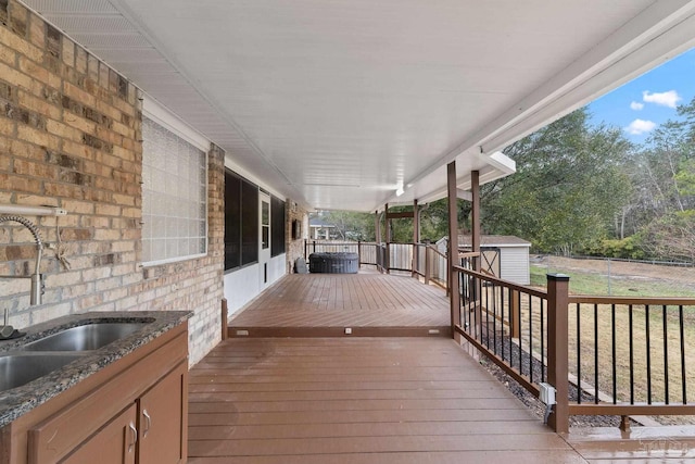 wooden terrace featuring an outbuilding, a storage unit, and a sink