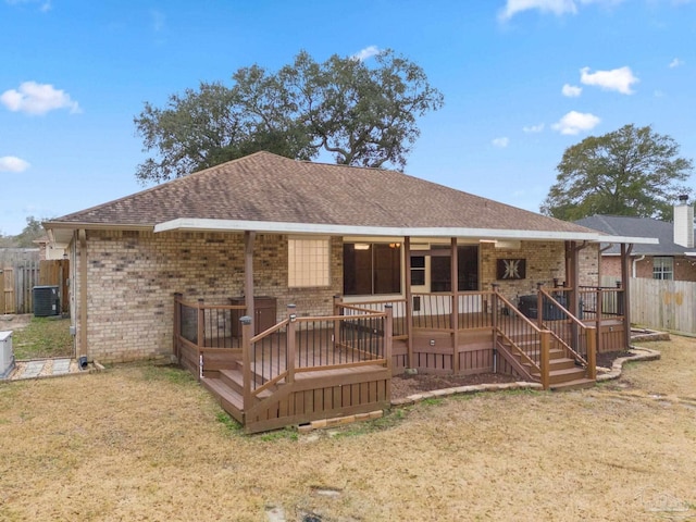 view of front of property featuring fence, central AC unit, brick siding, and roof with shingles