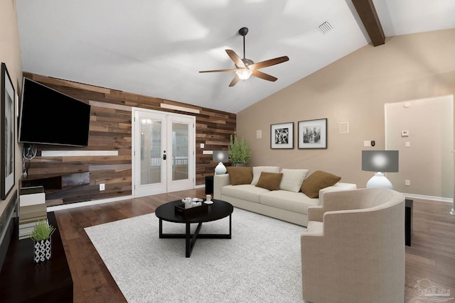 living area with visible vents, beam ceiling, wood finished floors, french doors, and wooden walls