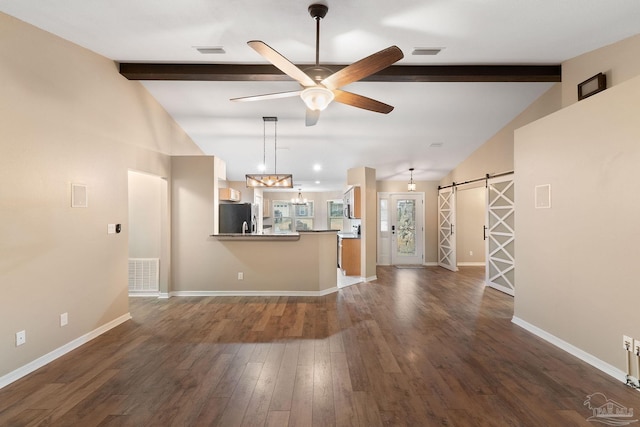 unfurnished living room featuring a barn door, lofted ceiling with beams, and visible vents