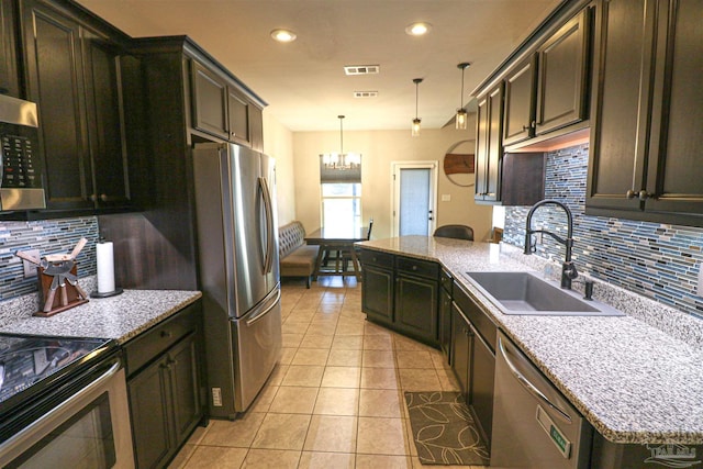 kitchen with light tile patterned floors, stainless steel appliances, backsplash, pendant lighting, and sink