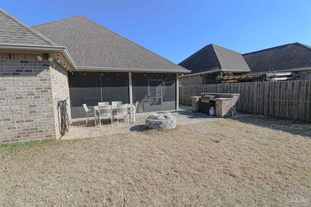 back of house featuring a sunroom, a fire pit, a lawn, and a patio