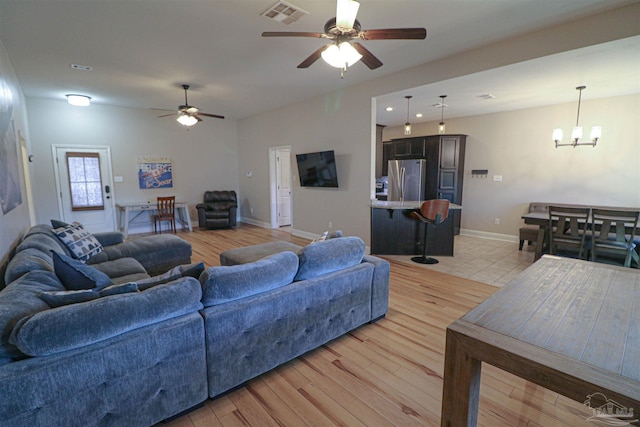 living room with ceiling fan with notable chandelier and light wood-type flooring