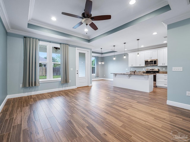 unfurnished living room featuring ceiling fan, a raised ceiling, crown molding, and light hardwood / wood-style flooring