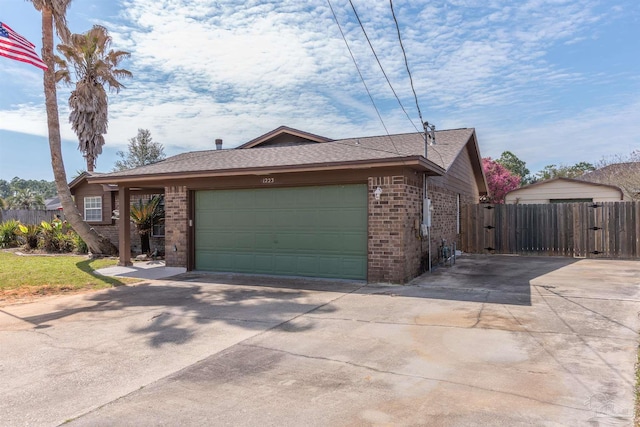 single story home featuring a garage, brick siding, fence, concrete driveway, and a gate