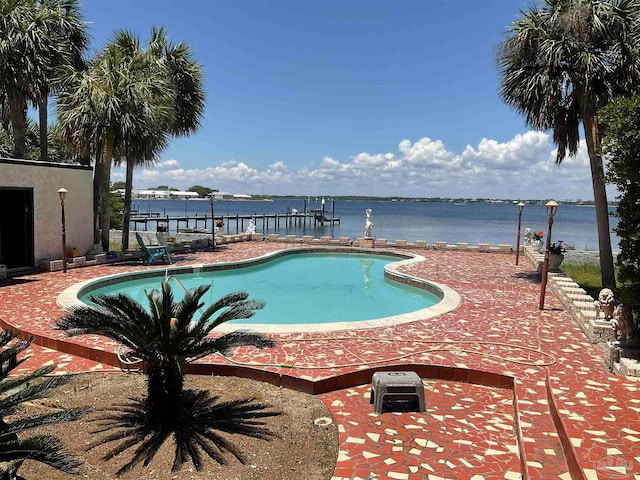 view of swimming pool featuring a dock, a water view, and a patio