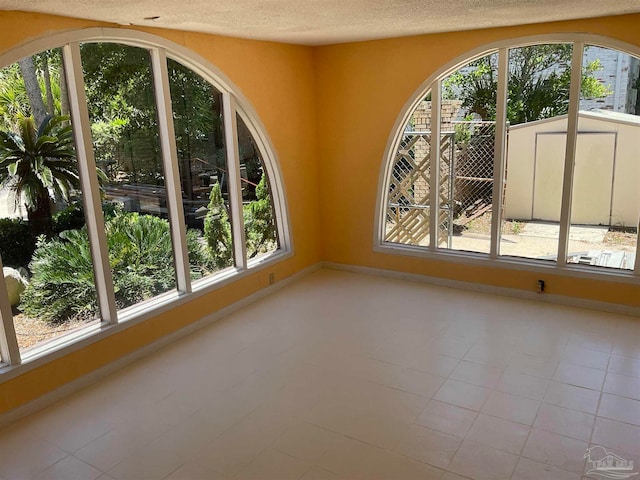 unfurnished room with light tile patterned floors and a textured ceiling