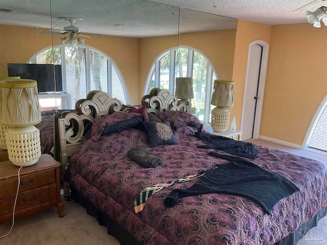 bedroom with a textured ceiling, light colored carpet, and ceiling fan