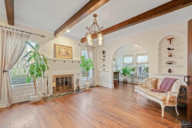 living area featuring wood-type flooring, a healthy amount of sunlight, built in features, and beam ceiling