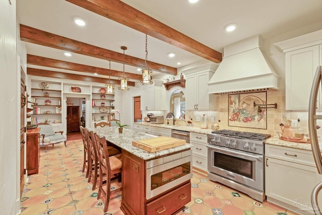 kitchen featuring premium range hood, a kitchen island, decorative light fixtures, stainless steel appliances, and light stone countertops