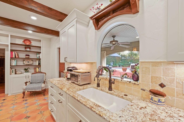 kitchen with white cabinetry, sink, and light stone counters