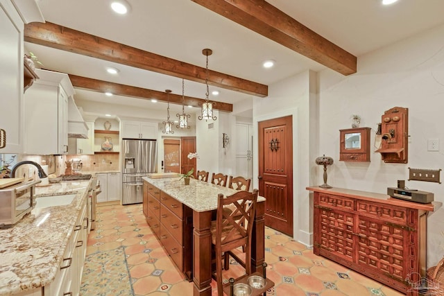 kitchen featuring white cabinetry, stainless steel appliances, light stone countertops, and a kitchen island