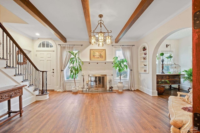 entrance foyer featuring crown molding, hardwood / wood-style floors, a notable chandelier, and beam ceiling