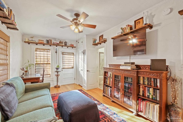 living room with ornamental molding, ceiling fan, and light hardwood / wood-style flooring