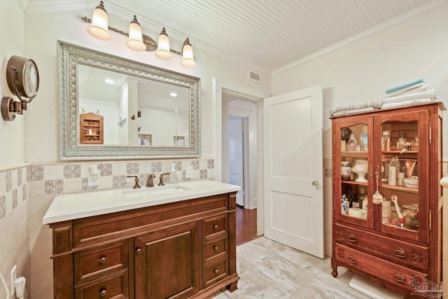 bathroom featuring vanity, ornamental molding, and tile walls