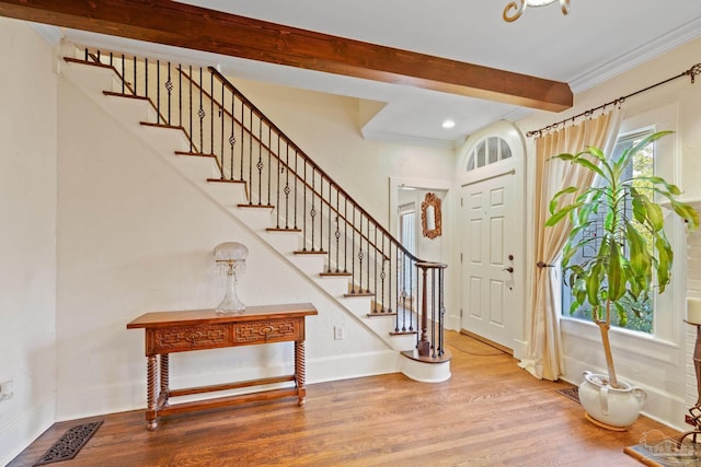 foyer entrance featuring crown molding, hardwood / wood-style floors, and beam ceiling