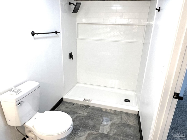 bathroom featuring a tile shower and toilet