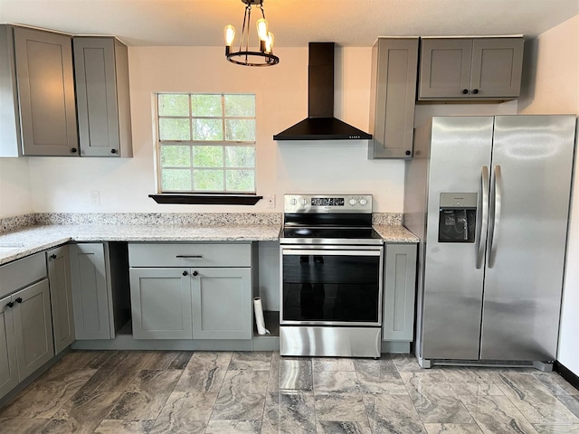 kitchen with gray cabinets, appliances with stainless steel finishes, wall chimney exhaust hood, and light stone counters