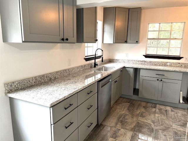 kitchen with sink, stainless steel dishwasher, gray cabinetry, and light stone counters