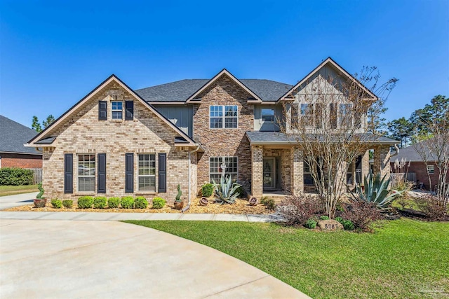 view of front of house with a front yard, brick siding, and roof with shingles