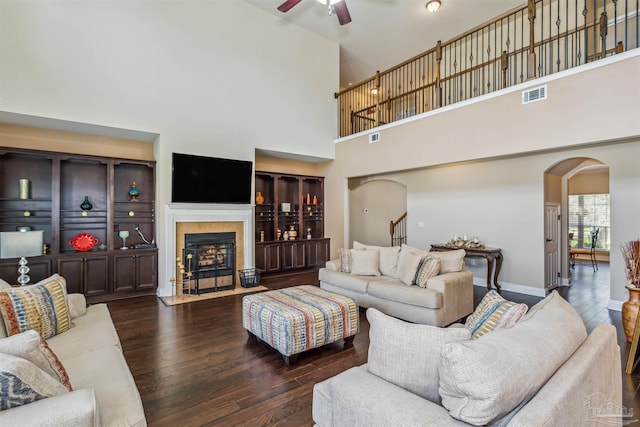 living room featuring wood finished floors, visible vents, arched walkways, ceiling fan, and stairs