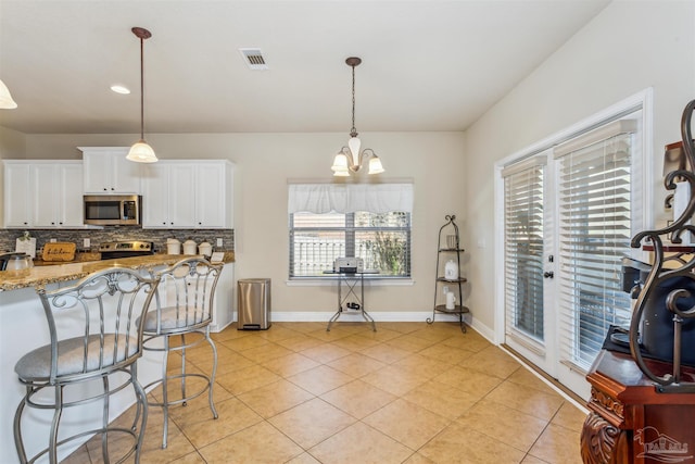 kitchen featuring visible vents, backsplash, white cabinetry, appliances with stainless steel finishes, and light stone countertops