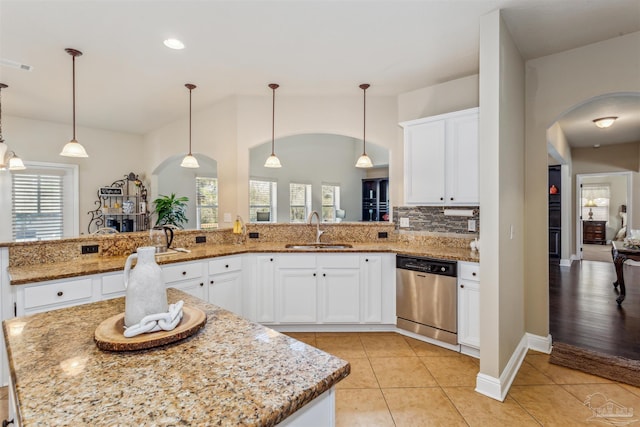 kitchen featuring a sink, arched walkways, dishwasher, and light tile patterned floors