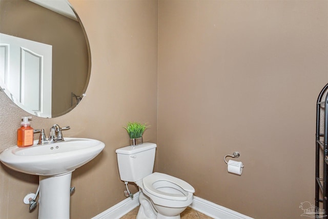 bathroom with baseboards, toilet, and tile patterned flooring