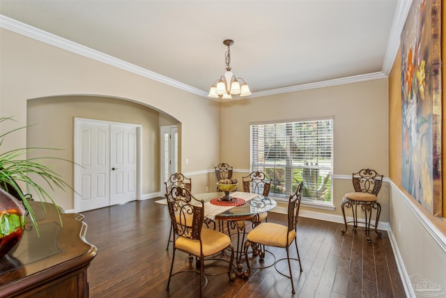 dining area featuring arched walkways, a notable chandelier, ornamental molding, and dark wood-style flooring