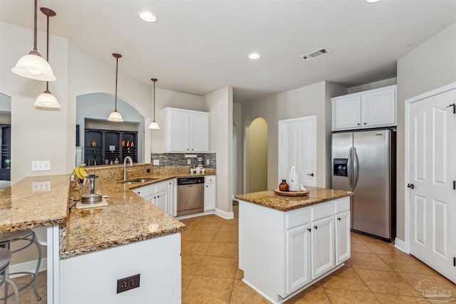 kitchen with visible vents, appliances with stainless steel finishes, a peninsula, arched walkways, and a sink